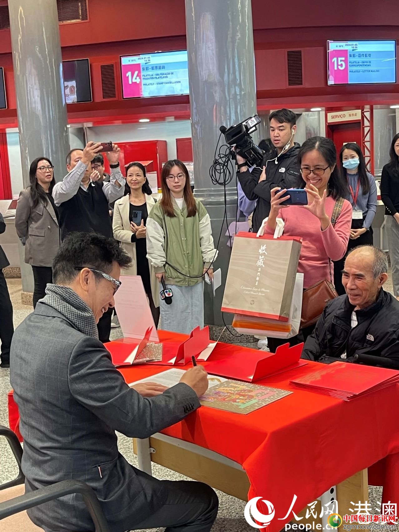 图为邮票设计师林子恩（左）为集邮爱好者签名。（本报记者富子梅摄）
